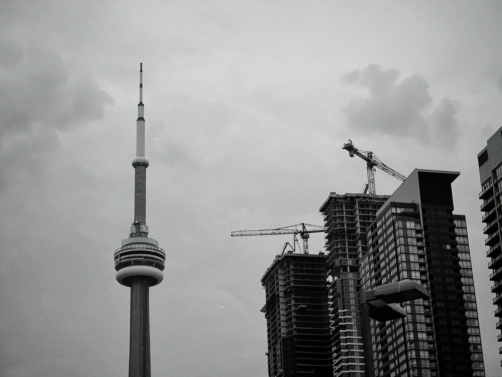 Monochrome image showcasing the CN Tower and surrounding skyscrapers under cloudy skies.